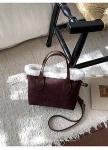 Detail of a brown suede bucket bag with white faux fur trim in a cozy winter setting