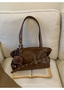 Close-up of retro brown oil wax leather tote bag with eyelet straps on white sofa
