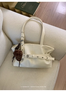 Detail of cream white PU leather tote with belt buckle strap and small hat pendant