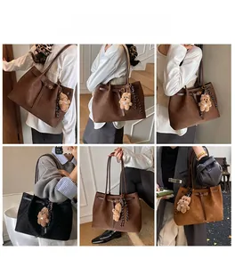 Dettaglio della borsa tote intrecciata con fibbia in pelle e ciondolo a orsetto