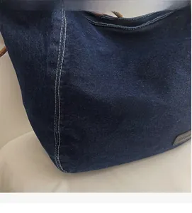 Detailed close-up of dark indigo denim fabric with white double stitching and leather label