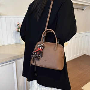 Detail of dark brown shell bag with pebble leather texture and cute bear charm
