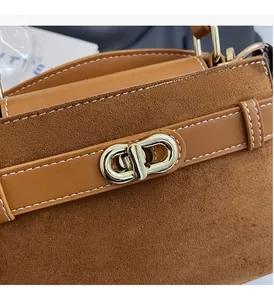 Detail aus braunem Leder und Wildleder mit goldenem Drehverschluss und sichtbaren Nähten