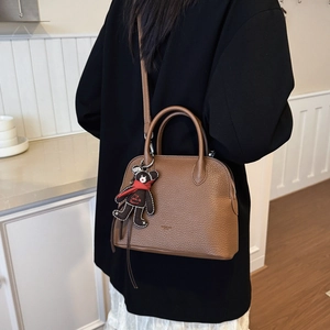 Brown lychee texture shell bag with a cute bear charm shown on a black suit