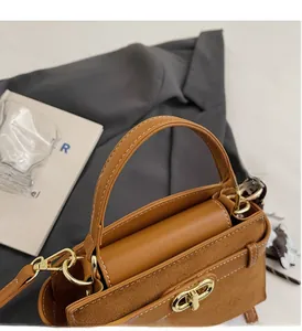 Detailansicht der Kontrastnähte und des goldenen Drehverschlusses an brauner Handtasche
