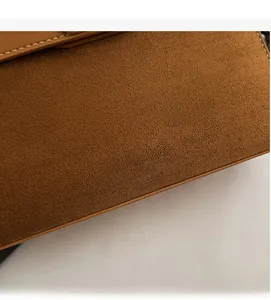 Nahaufnahme der braunen Wildledertasche mit weißen Kontrastnähten und modischem Aufdruck