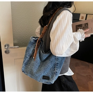 Détail du sac cabas en jean vintage avec bandoulière en corde tressée et patch cuir