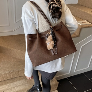 Dettaglio borsa shopper intrecciata marrone scuro con orsetto e foulard leopardato