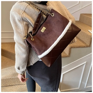 Detail of winter quilted brown bucket bag with faux fur trim and gold chain strap