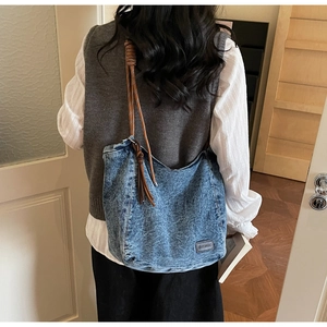 Détail d'un sac en denim délavé avec bandoulière en corde marron et étiquette de marque