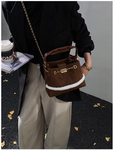 Detail of caramel suede bucket bag with white faux fur trim and gold chain strap