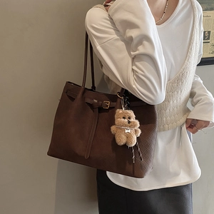 Dettaglio borsa tote marrone scuro con trama intrecciata e ciondolo orsetto con perle