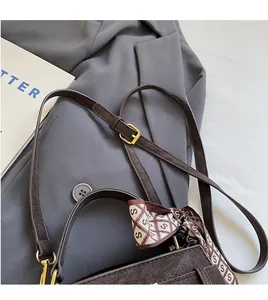 Close-up of brown pebbled leather handbag with adjustable strap and decorative scarf