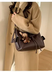 Détail du sac demi-lune en cuir marron foncé avec boucle dorée et breloque ours