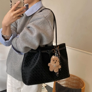 Dettaglio della borsa tote intrecciata nera con ciondolo a forma di orso e foulard in seta