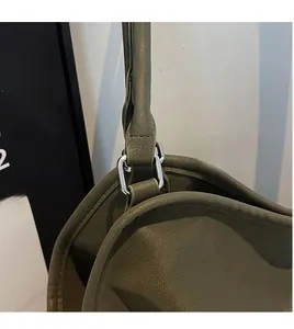 Detail of silver metal D-ring hardware and olive green lychee grain leather on tote bag