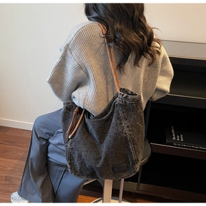 Détail du sac cabas en denim noir avec surpiqûres et bandoulière à nœud orange