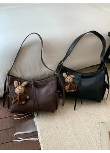 Détail de sacs bandoulière en cuir rétro avec cordons à glands et pendentif peluche mignon