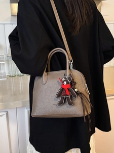 Minimalist grey lychee leather shell handbag with bear charm shown on a model back view