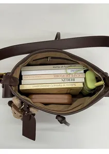 Intérieur spacieux du cabas en cuir marron avec livres, étui à lunettes et parapluie