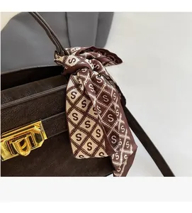 Macro shot of dark brown pebbled leather texture with gold metal rotary buckle and silk scarf