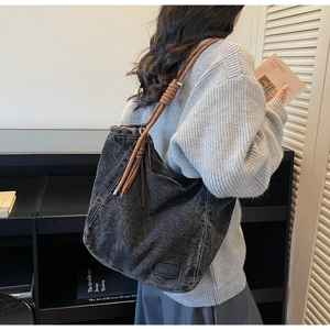 Detailed view of grey washed denim tote with brown rope strap and knot detail