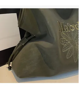 Detail of olive green soft tote bag featuring daisy embroidery and textured fabric