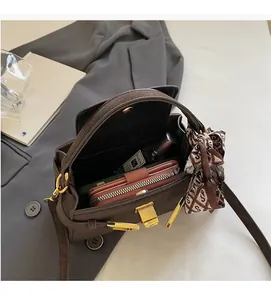 Detail showing the spacious interior of a brown suede handbag with a silk scarf handle