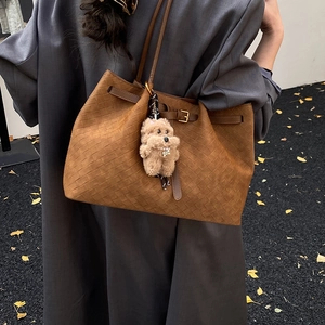 Dettaglio della borsa tote intrecciata marrone con fibbia e ciondolo a forma di cane