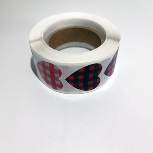 Roll of heart-shaped plaid stickers in red, black, and pink for Valentine gift wrapping