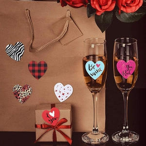 Macro shot of heart-shaped Valentine stickers on gift boxes with red roses and champagne