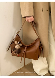 Détail du sac hobo en cuir marron avec lanières pendantes et breloque lapin en peluche