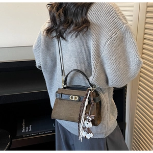 Braune Retro-Wildledertasche mit goldenem Verschluss und Hundeanhänger am Modell