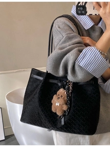 Elegante borsa tote intrecciata nera con ciondolo a forma di orso bruno vista laterale