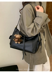 Détail du sac à bandoulière noir avec poche latérale et breloque ours en peluche