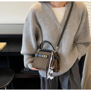 Detail der olivgrünen matten Tasche mit schwarzen Griffen und einem Hund-Anhänger