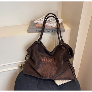 Close-up of a brown tote bag with daisy pattern and drawstrings on a black stool