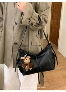 Détails de la boucle de réglage latérale et du charm ours sur le sac noir