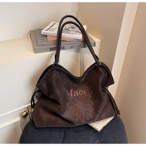 Detail of dark brown tote bag featuring daisy embroidery and drawstring side accents