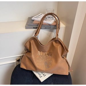 Detail of brown tote bag with Maodi embroidery and daisy pattern on leather surface