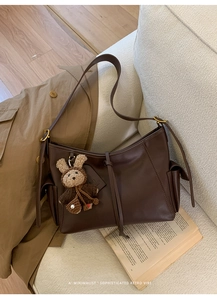 Détail d'un sac cabas rétro marron foncé avec un charm ours mignon et une texture en cuir