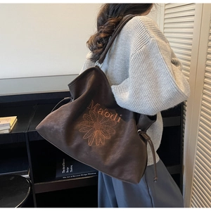 Close-up of large brown suede tote bag with floral embroidery and adjustable side drawstrings