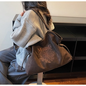 Detail of dark brown suede tote bag featuring daisy embroidery and drawstring closure