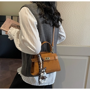Nahaufnahme der braunen Retro-Tasche mit Metallschloss und Schnauzer-Anhänger
