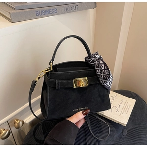 Detail of black crossbody bag with gold logo, silk scarf handle, and metal clasp
