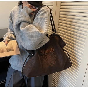 Detail view of large dark brown tote bag with Maodi logo embroidery and drawstring closure