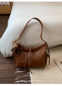 Gros plan sur la poche latérale du sac rétro marron et son petit ours en tricot