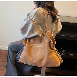 Detail of flower embroidery and drawstring design on large brown tote shoulder bag