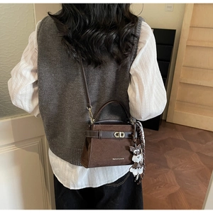 Detail der braunen Retro-Schultertasche mit Metallschloss, Seidenschal und Anhänger