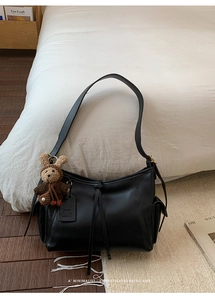 Détail du sac bandoulière en similicuir noir avec poches et pendentif lapin en peluche